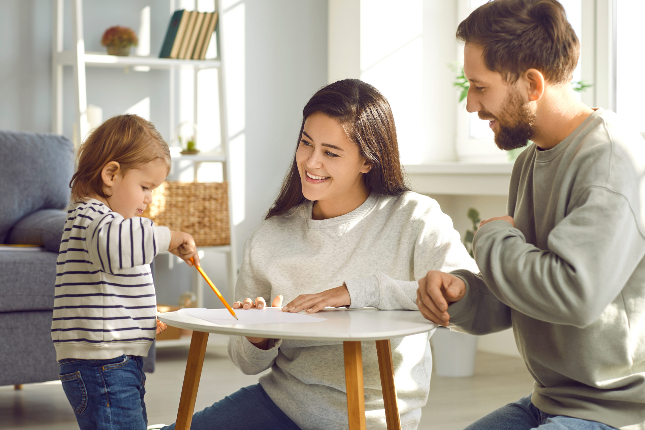 Des parents autour d'une table basse regardant leur enfant dessiner